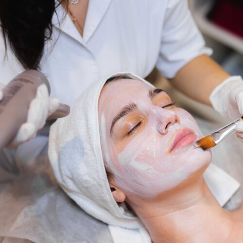 beautician-with-brush-applies-white-moisturizing-mask-face-young-girl-client-spa-beauty-salon